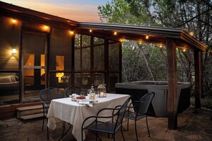 Eine Terrasse im Freien mit Esstisch, Whirlpool und Lichterkette.
