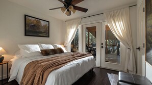 Una camera da letto con un letto grande, una ventola a soffitto e vista attraverso una porta in vetro.
