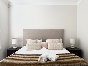 Una cama bien hecha con un edredón a rayas, cabecera y varias almohadas.
