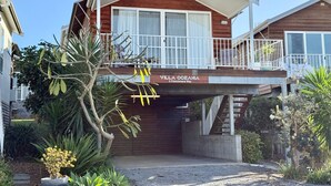 Edificio de madera de dos pisos con un balcón, un letrero que dice 'Villa Oceania' y un camino de entrada a la puerta.