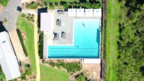 Vista aérea de una propiedad con piscina, terraza cubierta y jardín ajardinado.