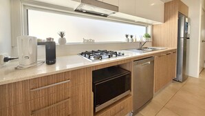 Una cocina moderna con estufa a gas, lavavajillas y refrigerador de acero inoxidable.