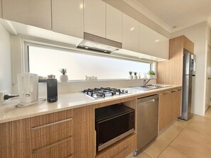 Una cocina moderna con estufa a gas, lavavajillas y refrigerador de acero inoxidable.