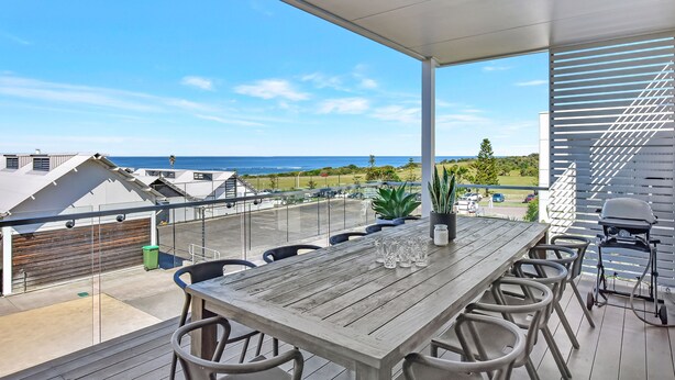 A covered outdoor dining area with a view of the ocean and a parking lot. - Bombora Beach House at Caves Beach (Caves Beach)
