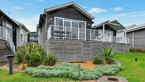 A modern two-story house with a balcony, surrounded by a well-maintained garden. - Mariner's Rest at Caves Beach Villas (Caves Beach)
