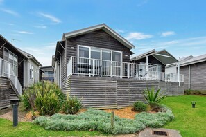 A modern two-story house with a balcony, surrounded by a well-maintained garden. - Mariner's Rest at Caves Beach Villas (Caves Beach)