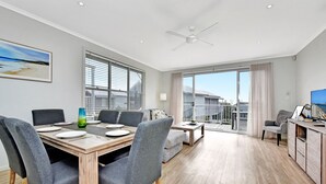 Een moderne woonkamer met een eethoek, grote ramen en een balkon.