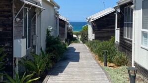 Une promenade en bois mène à une rangée de cabanes d’où l’on a une vue sur l’océan.