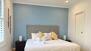 Une chambre à coucher avec un grand lit, une tête de lit, des tables de chevet et une petite table de nuit.