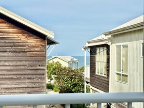 Un bâtiment en bois doté d’un balcon, situé à côté d’un bâtiment blanc avec une fenêtre, et donnant sur une étendue d’eau.