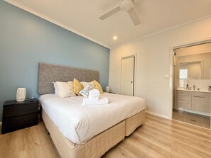 Une chambre à coucher avec un lit, une table de chevet et une salle de bain visible à travers une porte ouverte.