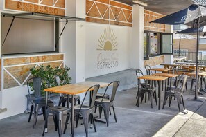 Un espace extérieur aménagé avec des tables et des chaises, une enseigne indiquant « Ocean Soul Espresso », et un panneau affichant le menu intitulé « Wild ».