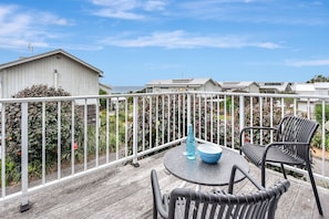 Una terraza con mobiliario exterior, una mesa y una silla, con vistas a una zona residencial con casas y cielo despejado.