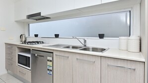Una cocina moderna con un lavamanos de acero inoxidable, un lavavajillas empotrado y un microondas.