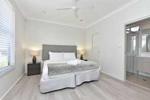 Une chambre à coucher avec un lit, des lampes de chevet, un ventilateur de plafond et un dressing.