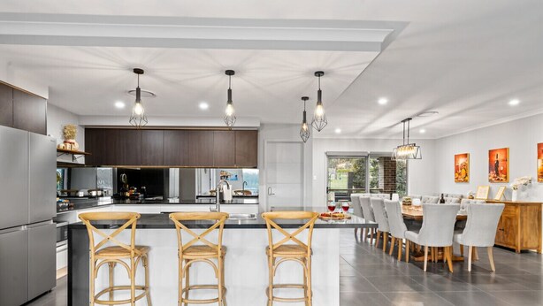 Una cucina moderna con isola centrale, sgabelli da bar e luci a sospensione.