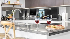 Una cucina moderna con isola centrale, due bicchieri di vino e un tagliere di salumi.