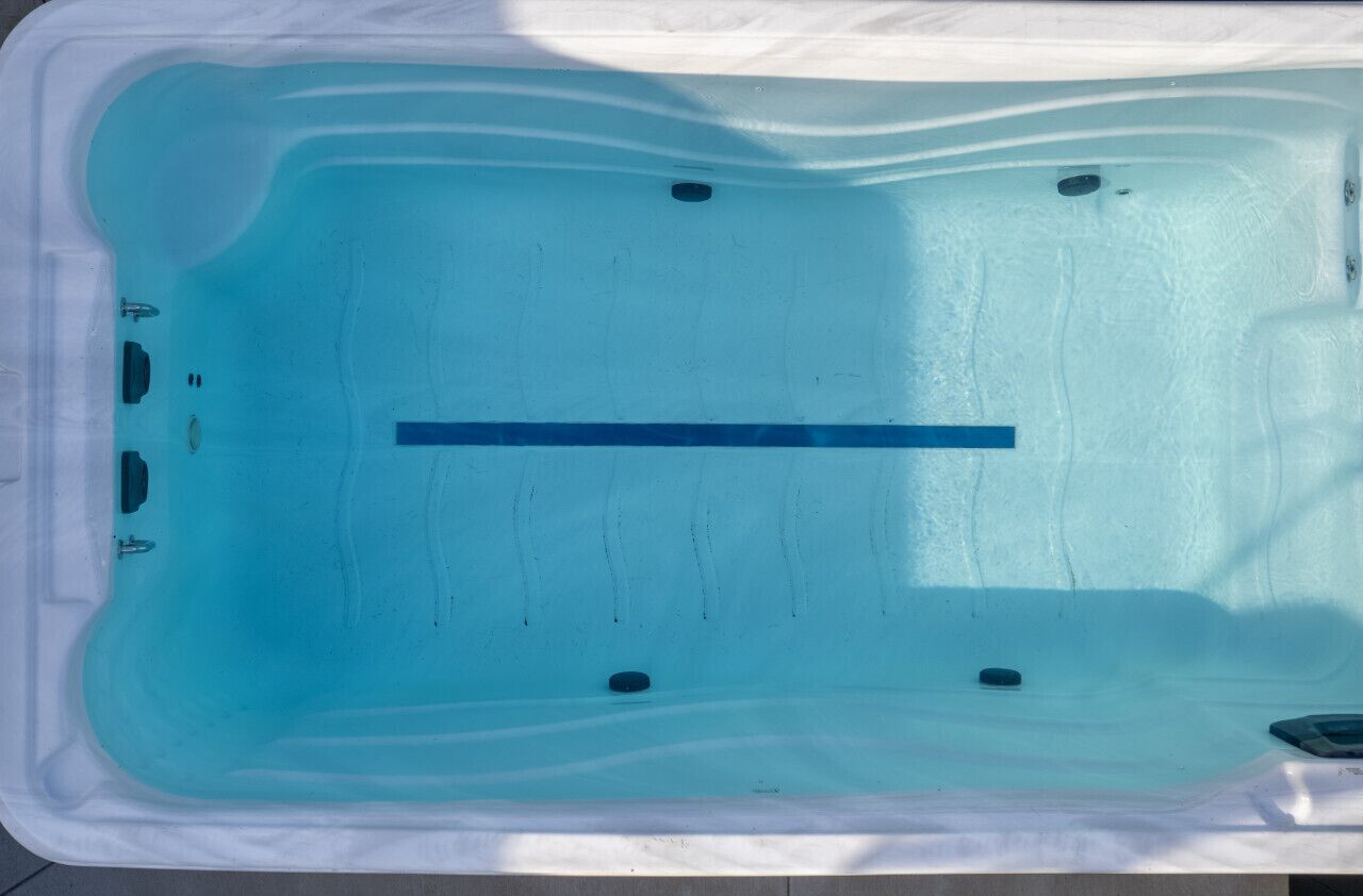 Vista clara de un jacuzzi con interior azul, un desagüe y un panel de control.