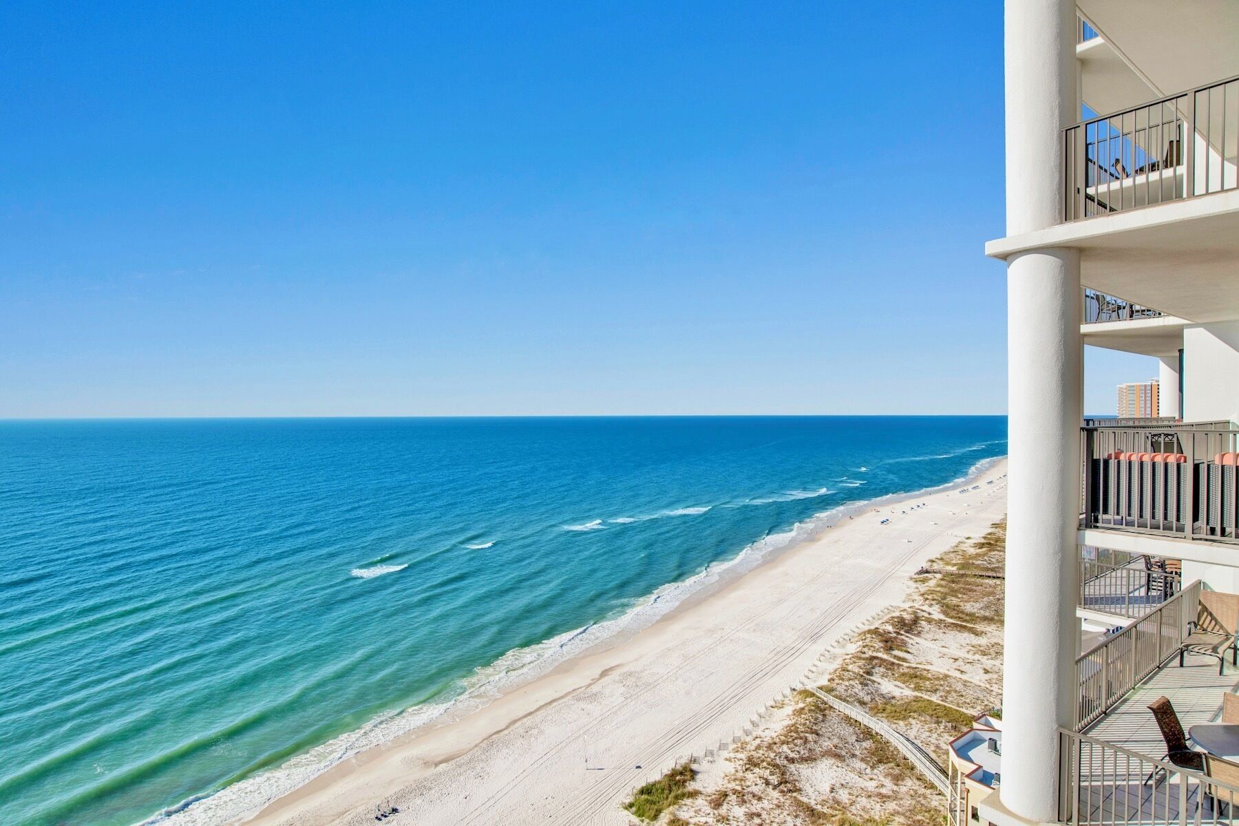 Un hotel frente a la playa con un balcón con vista al océano.