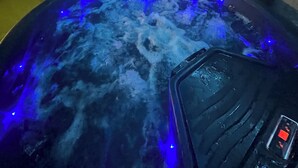 A hot tub with blue LED lights, a control panel, and a stone wall in the background. - "Atelier du spa" in the heart of Avranches near Mont Saint Michel  (Avranches)