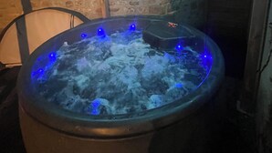 A hot tub with blue LED lights, surrounded by stone walls and a wooden ceiling. - "Atelier du spa" in the heart of Avranches near Mont Saint Michel  (Avranches)