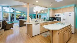 A modern kitchen with a central island, wooden cabinets, and a large window providing natural light.