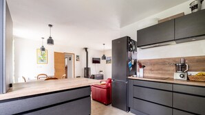 Une cuisine moderne avec des meubles de couleur sombre, une chaise rouge et un plan de travail en bois.