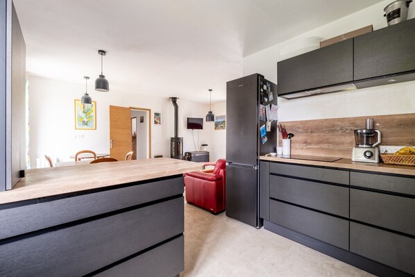 A modern kitchen with dark cabinetry, a red chair, and a wooden countertop.
