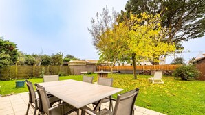 Une terrasse avec une table et des chaises, un arbre et une clôture en bois.