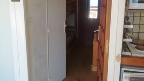 A narrow hallway with a wooden floor, a white door, and a kitchen area with a microwave and cabinets. - Studio 'Pathabac' with Mountain View and Balcony (Auris)