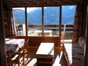 Una habitación con un ventanal grande, muebles de madera y vistas a montañas.