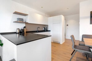 A modern kitchen with white cabinets, a black countertop, and a dining area with a table and chairs.