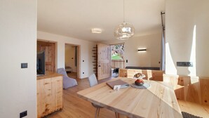 Un interior moderno con una mesa de comedor de madera, una lámpara colgante y vistas al exterior.