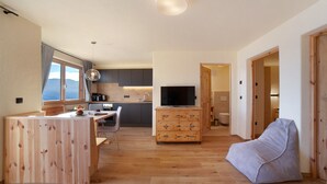 Un espacio moderno para vivir con comedor de madera, televisor y sillón informal.