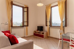 Ein Wohnzimmer mit Sofa, TV-Schrank und einem Tisch mit Stühlen.