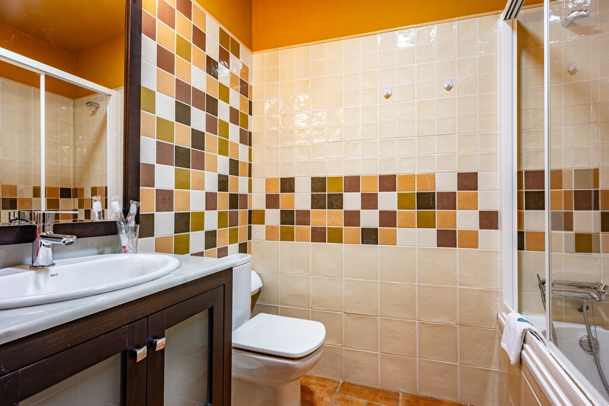 Een badkamer met een betegelde douche, een wastafel en een toilet.
