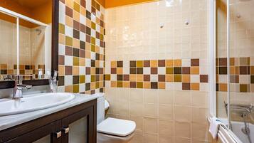 Een badkamer met een betegelde douche, een wastafel en een toilet.