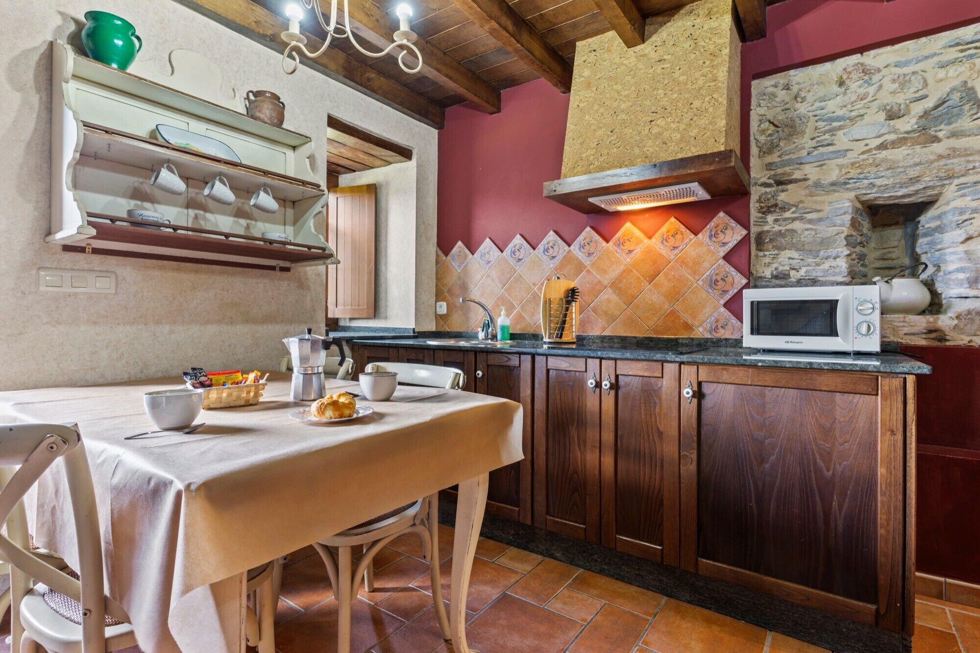 Una cocina con armarios de madera, microondas, cafetera y salpicadero de azulejos.