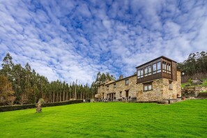 A stone building with large windows and a green lawn. - Country House 'Eiron' with Shared Terrace, Private Garden and Wi-Fi (ESPASANTE)