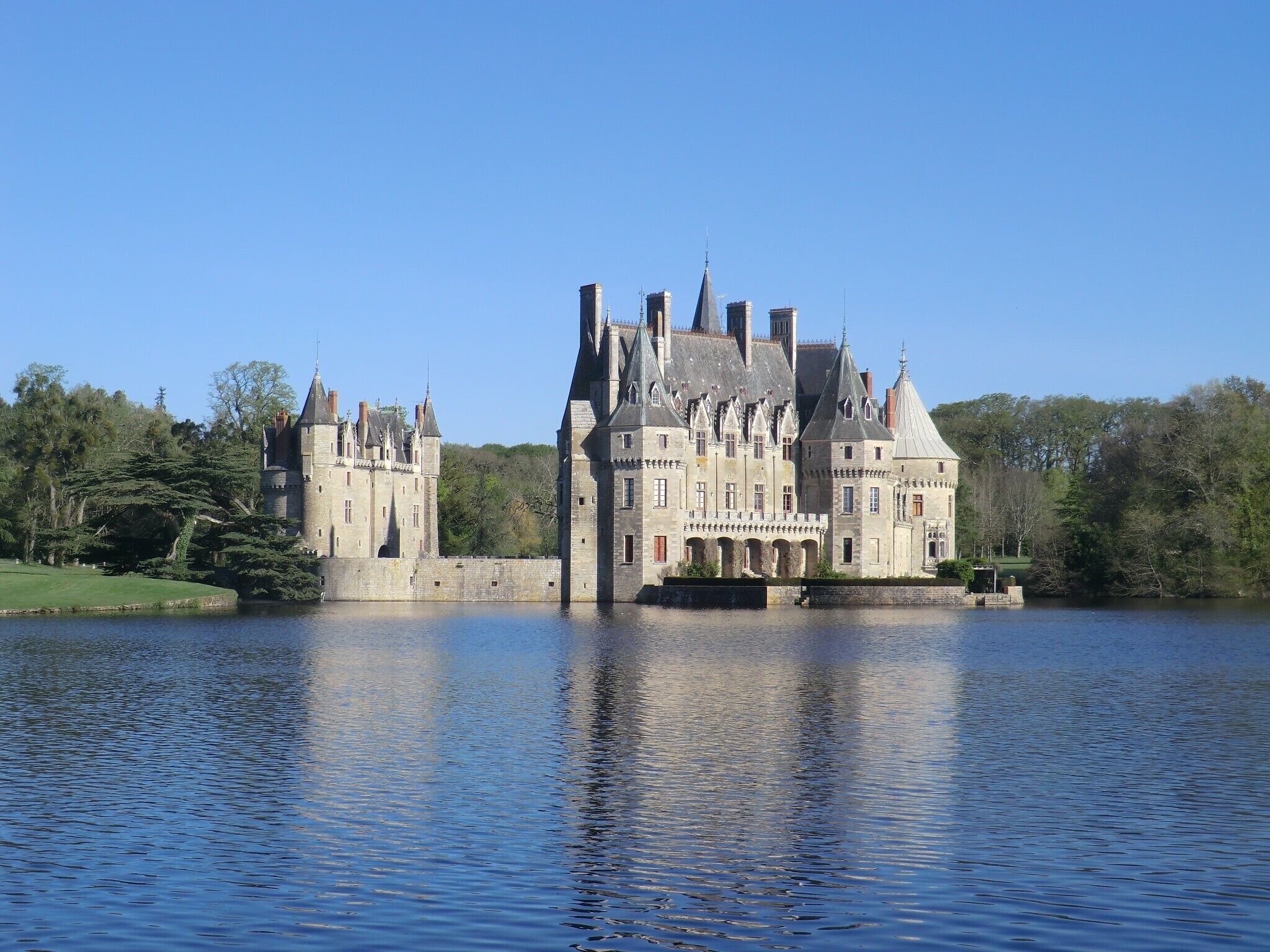 Een historisch kasteel met meerdere torens, gelegen aan een rustig meer.