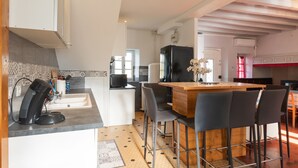 A modern kitchen with a bar area, a refrigerator, and a coffee machine. - La Maison Du Soleil - L'aulhère, Jacuzzi, Terrace, Air Conditioning, Sleeps 6 (Ledeuix)