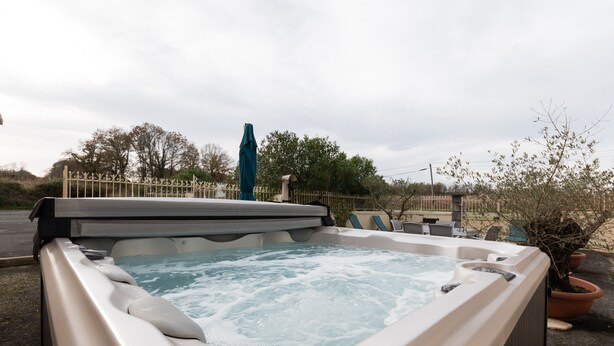 A hot tub with a metal railing, surrounded by a fence and potted plants. - La Maison Du Soleil - L'aulhère, Jacuzzi, Terrace, Air Conditioning, Sleeps 6 (Ledeuix)