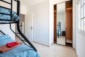 Ein Schlafzimmer mit Etagenbett, Kleiderschrank und Schiebetürenschrank.