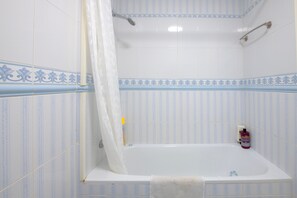 Ein Badezimmer mit Badewanne, Duschvorhang und Handtuchhalter.