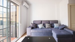Una sala de estar con un sofá gris, una mesa de centro negra y un ventanal corredero que da a un espacio al aire libre.