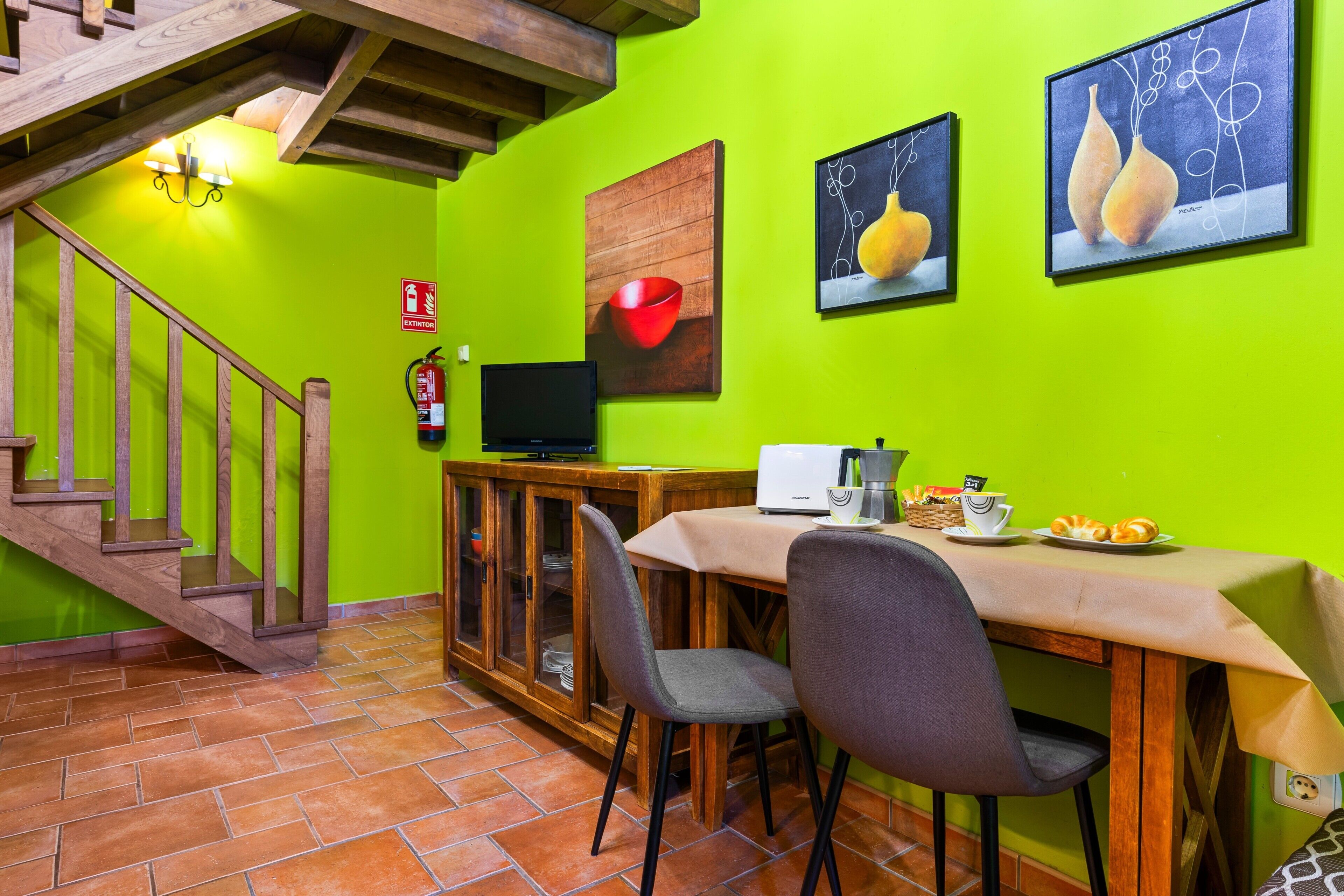 Un espace repas comprenant une table, des chaises, un extincteur et des œuvres d’art accrochées au mur.
