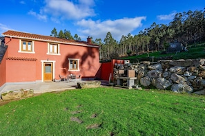 A two-story house with a red exterior, a stone wall, and a grassy yard. - Country House 'Esteiro' with Shared Garden and Wi-Fi (Espesante)