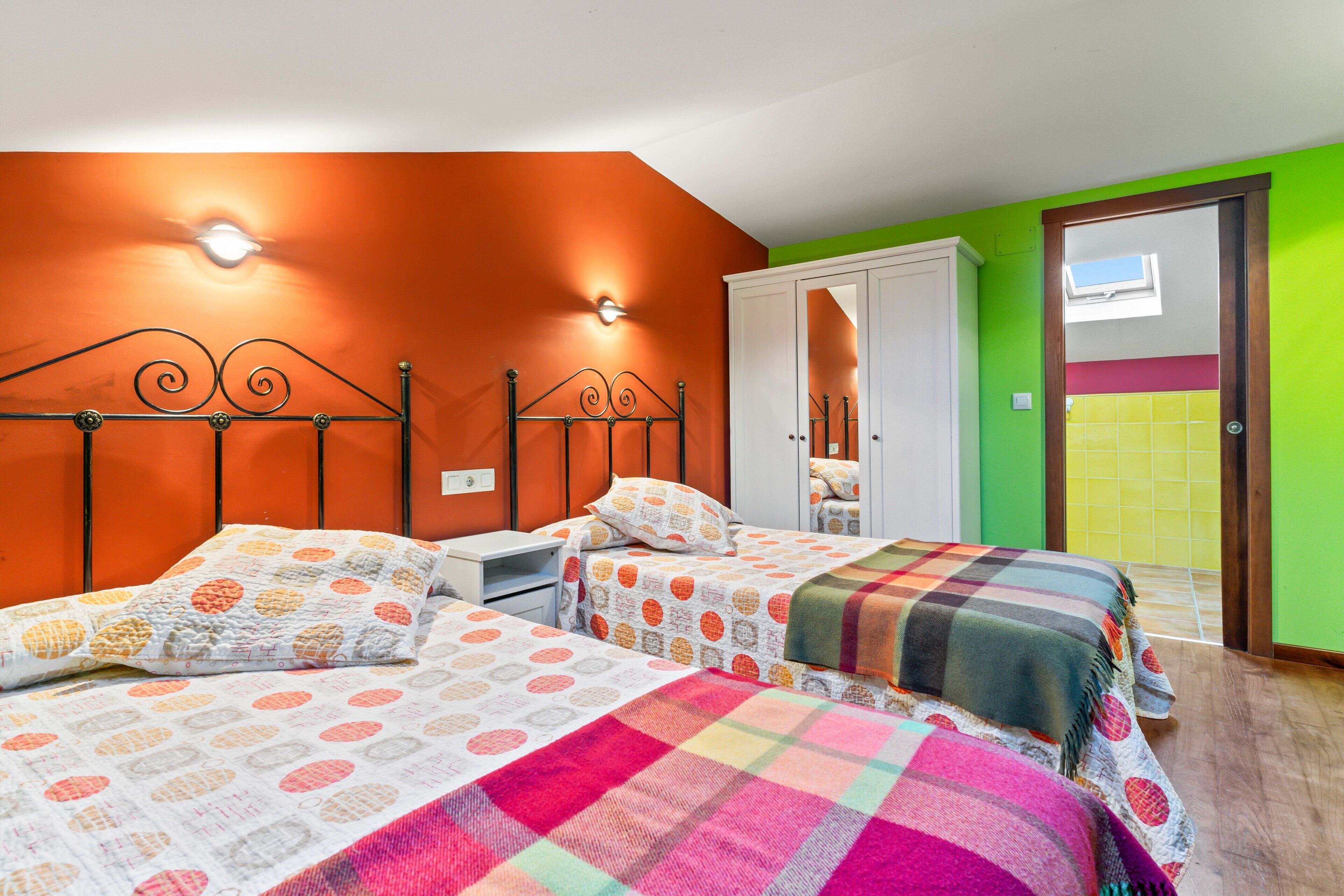 A room with two beds, a wardrobe, and a mirror.
