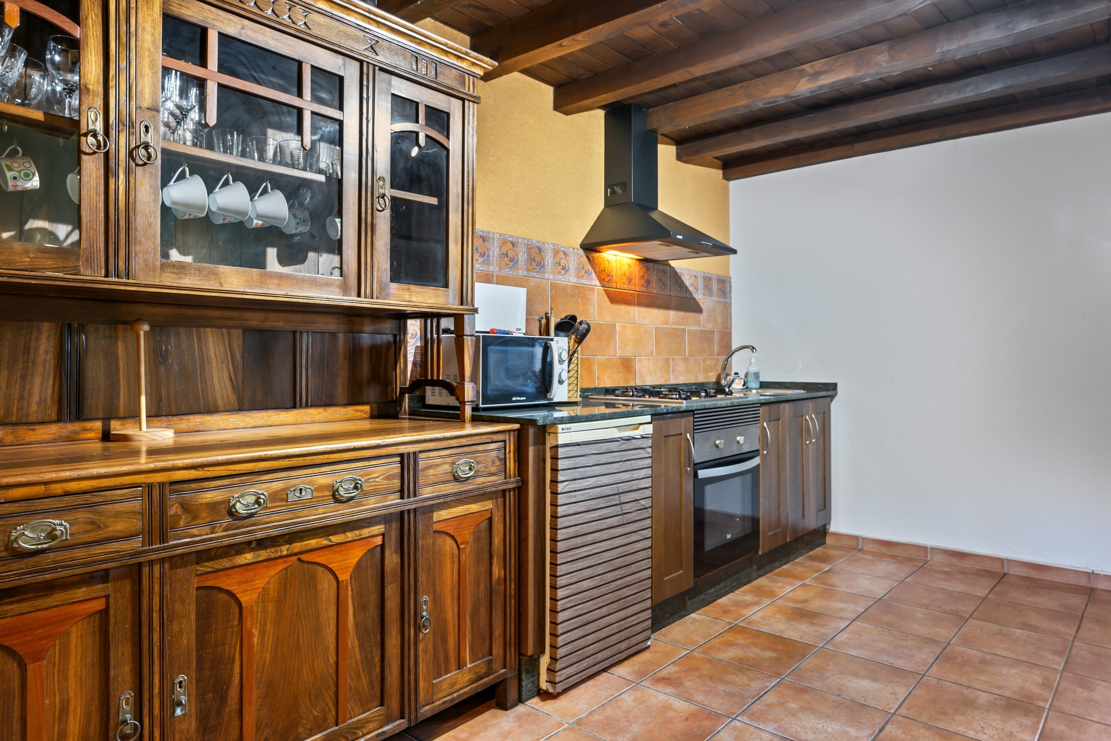 Une cuisine avec des meubles de rangement en bois, une cuisinière et un four à micro-ondes.
