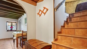 Una escalera con escalones de madera y barandilla, un comedor con mesa y sillas, y una ventana con vistas al exterior.